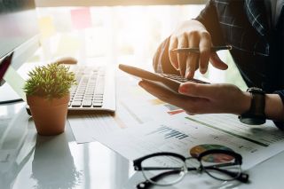 Foto: Mann mit Smartphone und Laptop